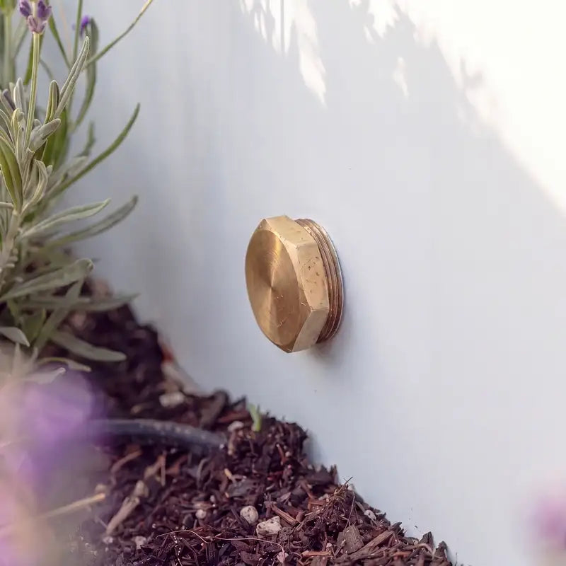 Detailbild von einem Ablassventil aus Messing eines Aluminium-Wasserbeckens im Garten.