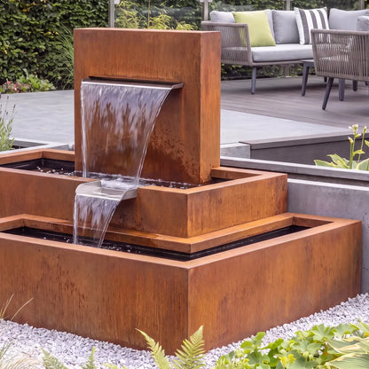 Modernes Wasserspiel mit einem stufigen Kaskadenbrunnen aus Cortenstahl in einem modernen Garten.