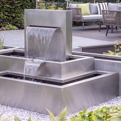 Modernes Wasserspiel mit einem stufigen Kaskadenbrunnen aus Edelstahl in einem modernen Garten.