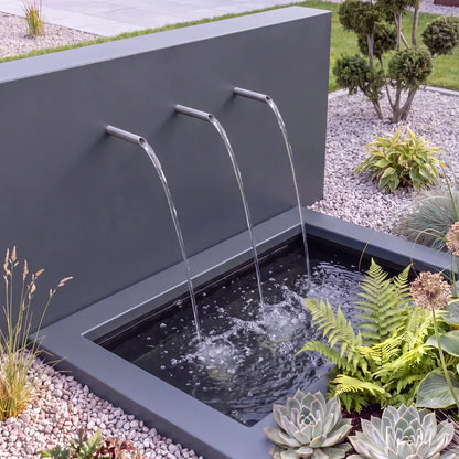 Freistehende Teichwand aus Aluminium mit drei Wassereinläufen vor einem versenkten Teichbecken aus GFK und Becken-Umrandung im Garten.