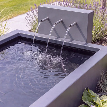 Aluminium-Wasserbecken mit einer Teichwand und Einläufen aus denen Wasser in das Metall-Becken fließt. 