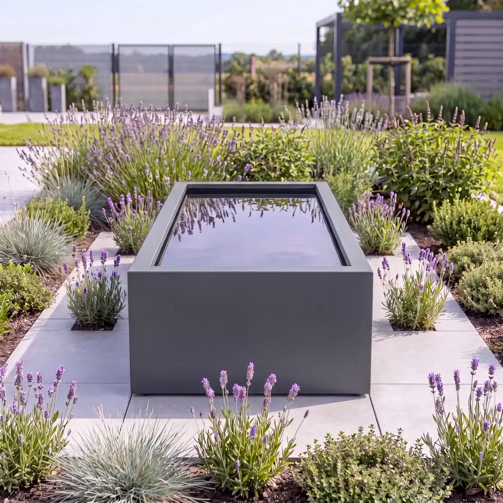 Rechteckiger Hochteich aus Aluminium mit spiegelndem Wasser auf einer Pflasterfläche in einem modernen Design-Garten.