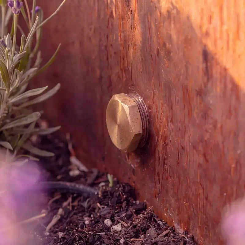 Detailbild von einem Ablassventil aus Messing eines Cortenstahl-Wasserbeckens im Garten.