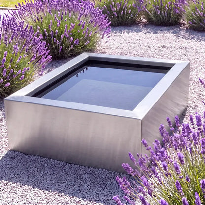 Edelstahl-Hochteich in quadratischer Form mit spiegelnder Wasseroberfläche in einem minimalen Garten.