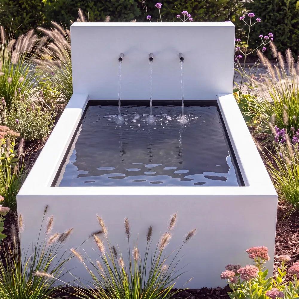 Metall-Teichbecken mit Wasserfall aus Aluminium und Rohr-Wasserauslauf  in einem grünen Blumenbeet.