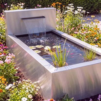 Teich aus Edelstahl mit Wasserfall und Wasserschütte in einem bunten Blumenbeet in einem Garten.