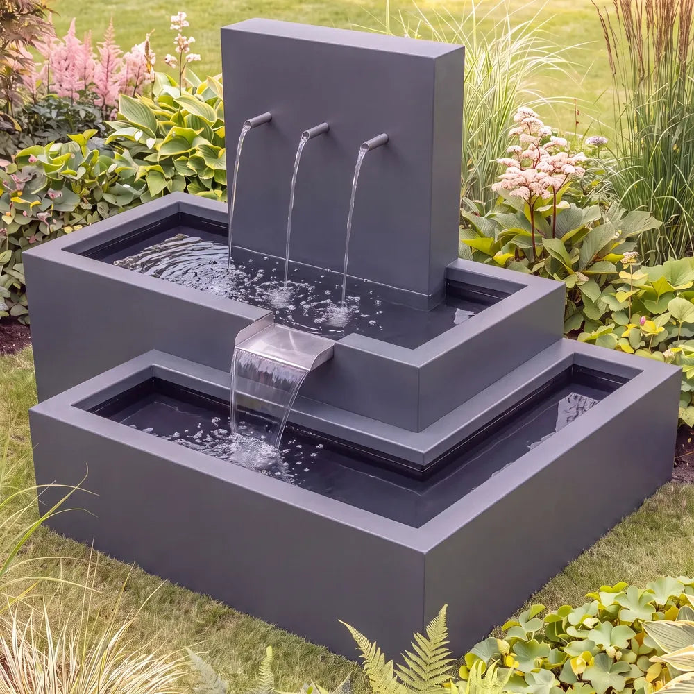 Metall-Wasserkaskade aus wetterfestem Aluminium und Rohreinläufen auf einer grünen Rasenfläche im Garten.