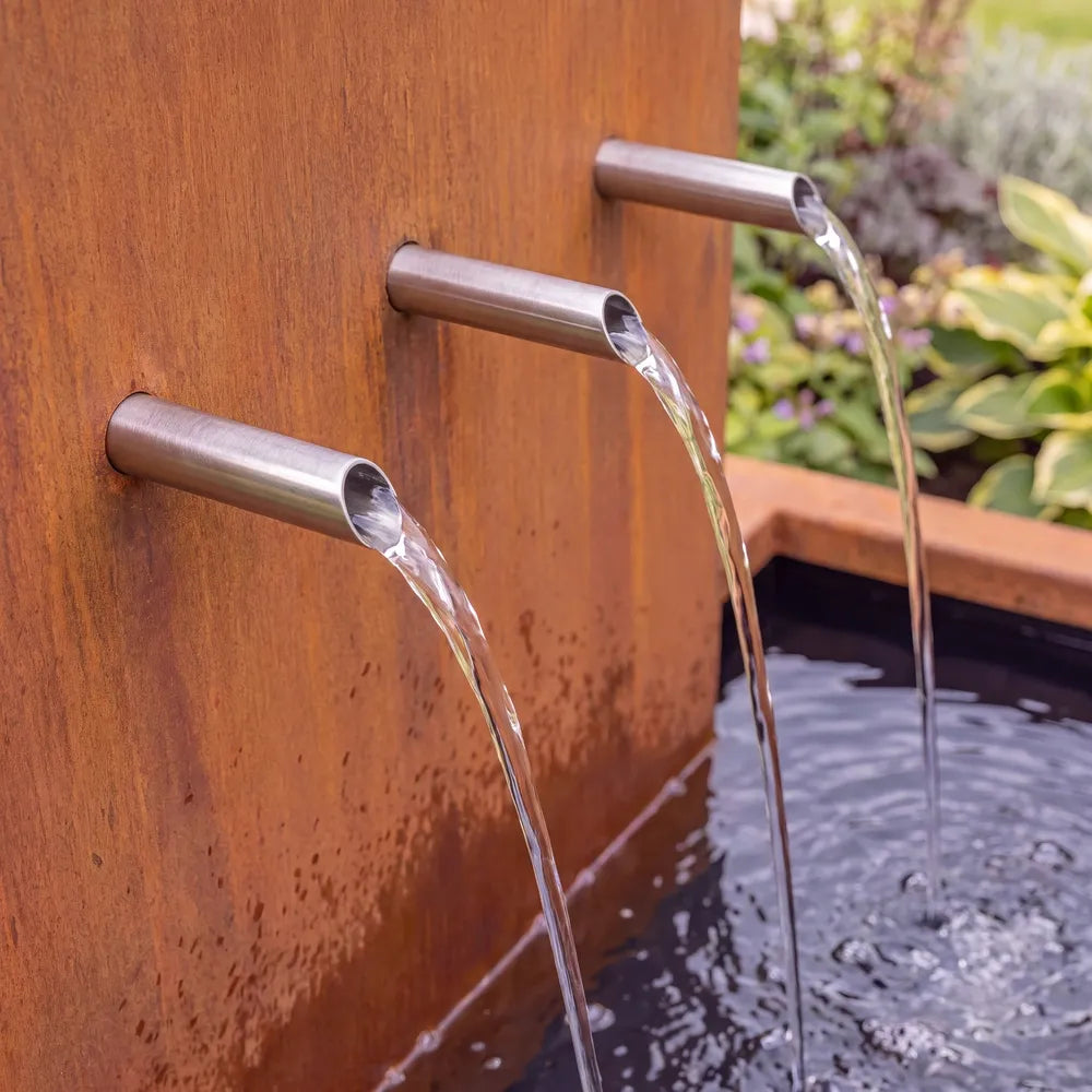 Edelstahl-Einlaufrohre an einer großen Wasserkaskade aus Cortenstahl mit mehrstufigen Teichbecken.